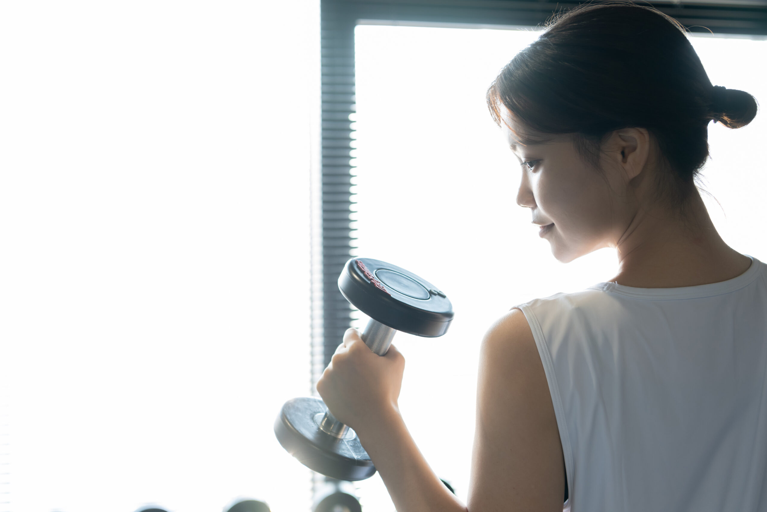ハコジム個室で集中してダンベルトレーニングを行う女性会員